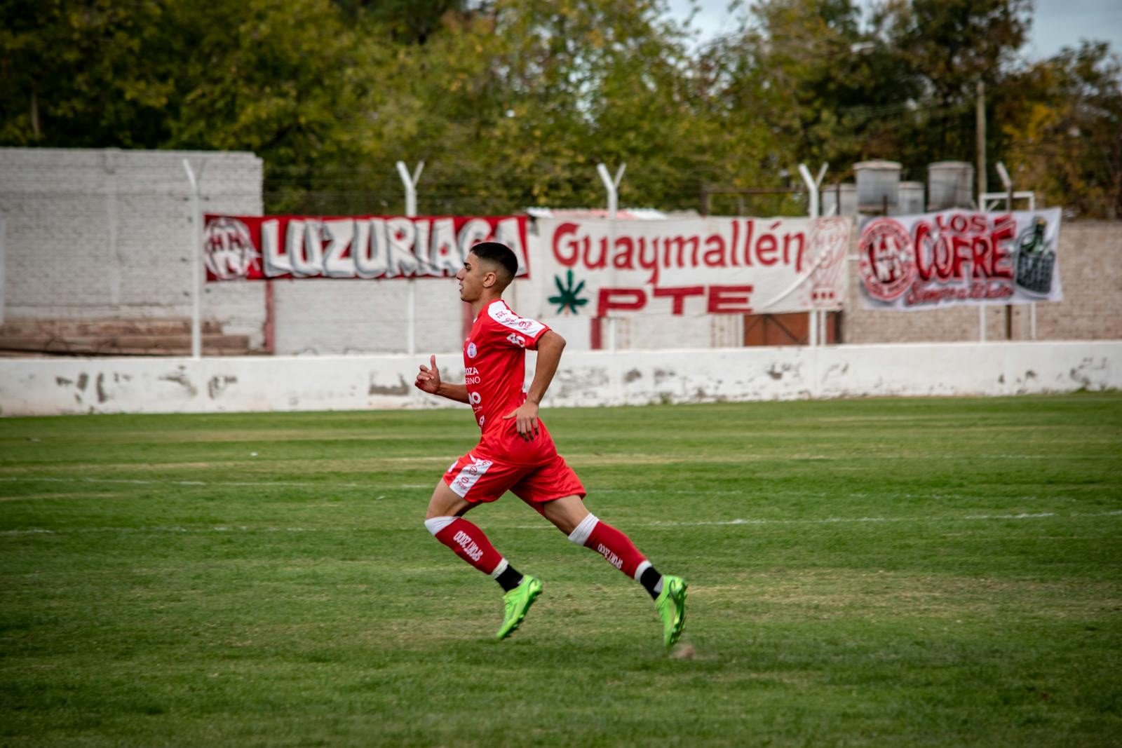 A Football Player Running on a Pitch during a Match