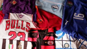 a pile of sports jerseys sitting on top of a bed